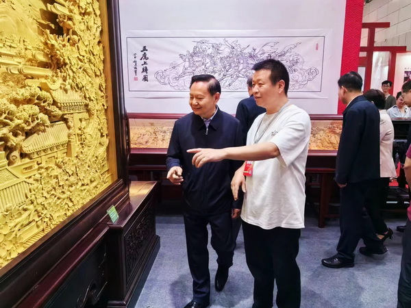 美聯(lián)紅木總設(shè)計胡冠軍（右）為中國輕工業(yè)聯(lián)合會張崇和會長（左）介紹《盛世繁華》大地屏